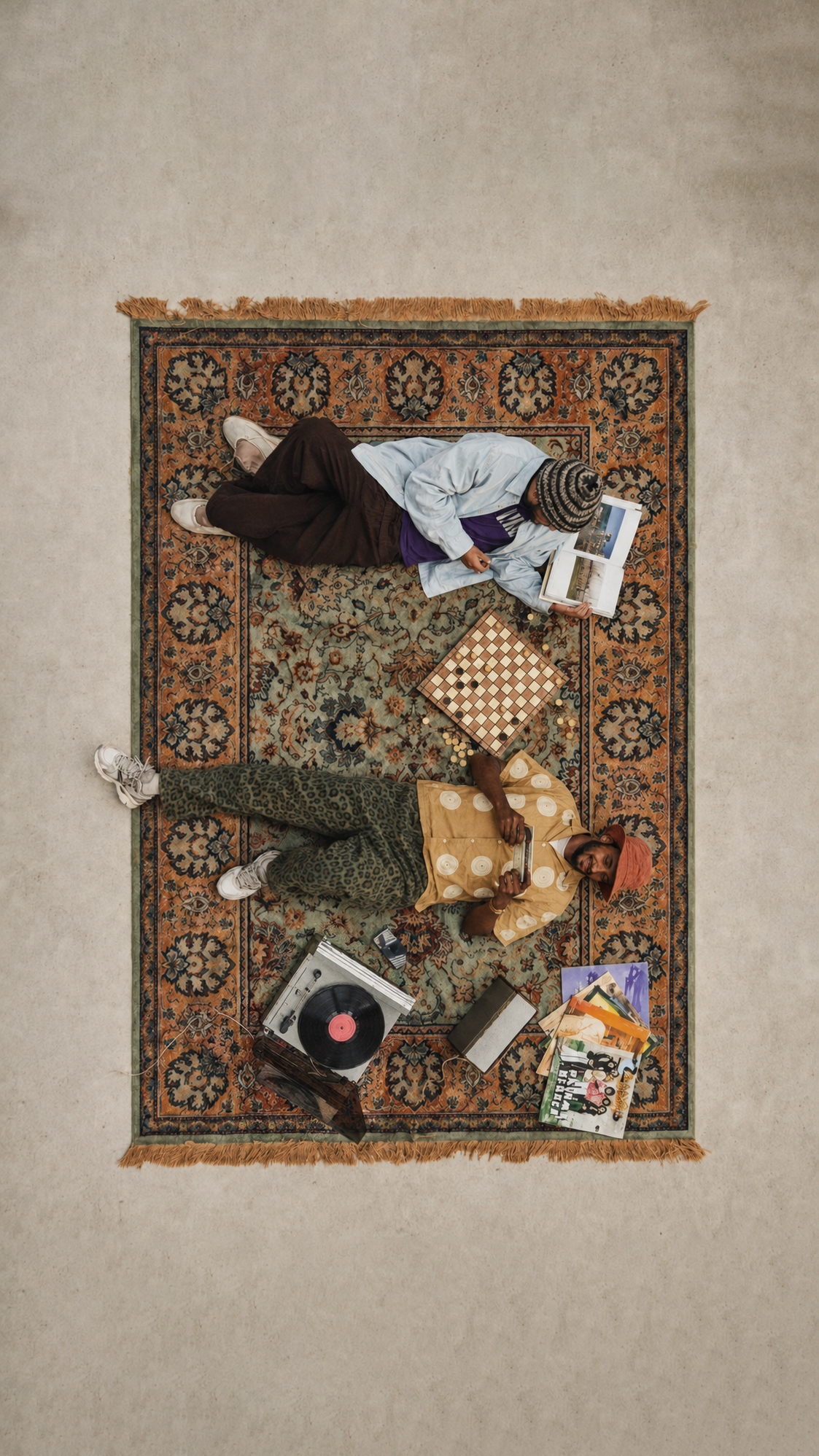 Two people relaxing on a patterned rug with books, games and records