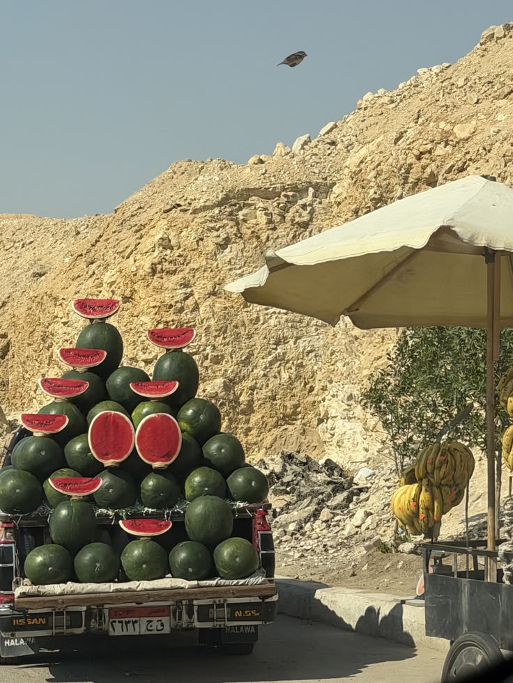 Truck stacked with watermelons beside a rocky roadside