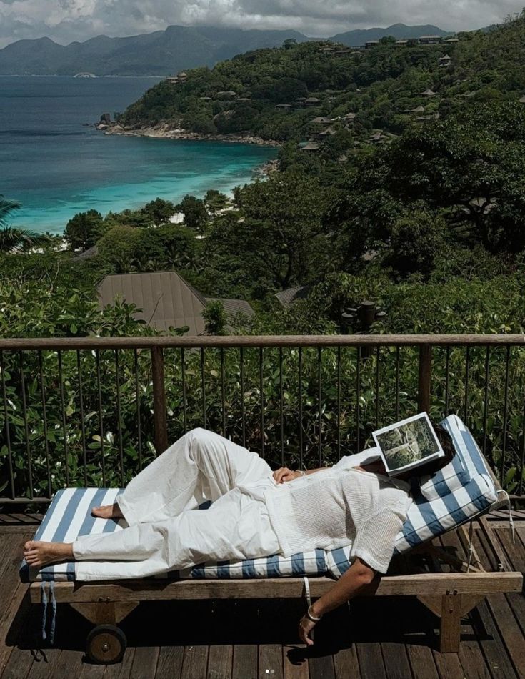 Person resting on a sun lounger overlooking a green coastline