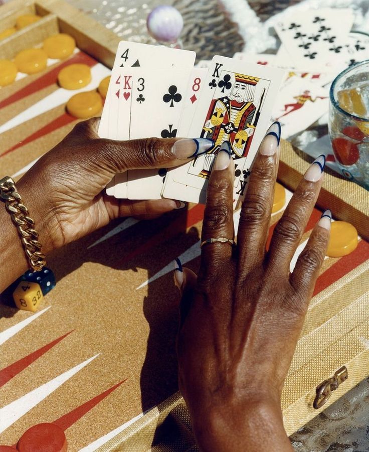 Hands holding playing cards over a backgammon board