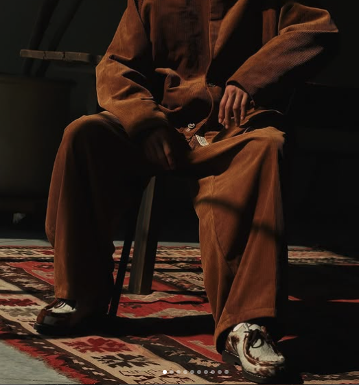 Wide brown corduroy trousers styled on a patterned rug