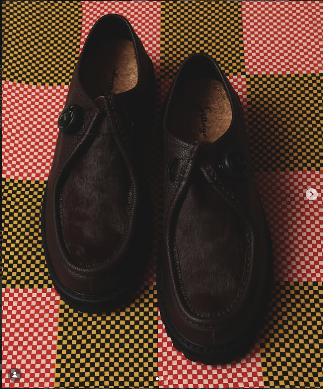 Dark brown shoes on a red, yellow and black checked textile