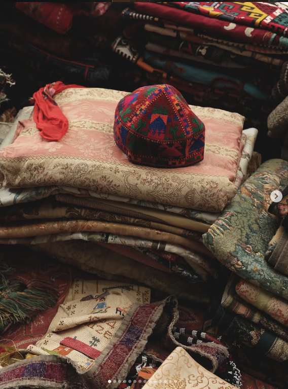 Stacks of traditional textiles with a colourful embroidered cap