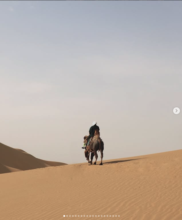 Rider crossing pale coastal dunes beneath an open sky