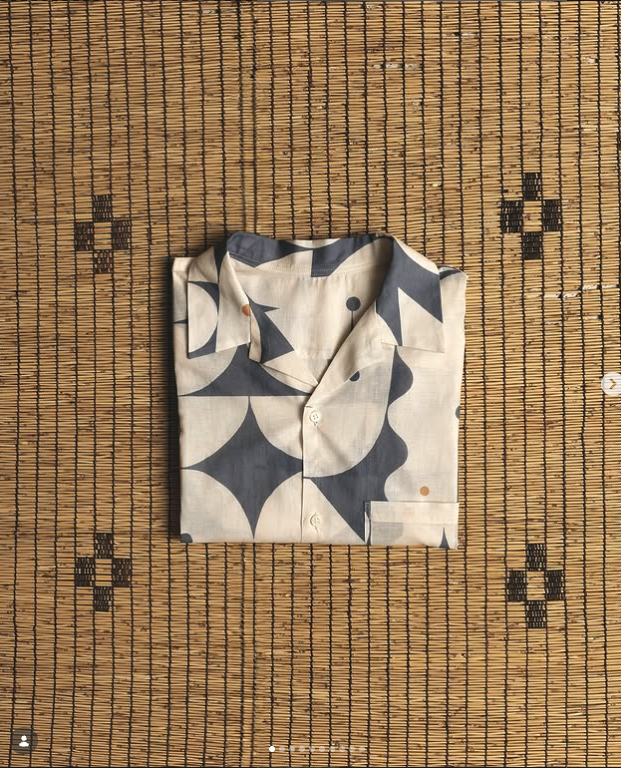 Folded printed shirt displayed on a woven mat