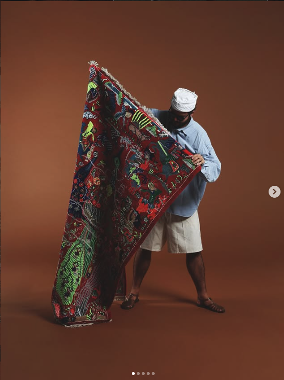 Large illustrated woven textile held open in a studio
