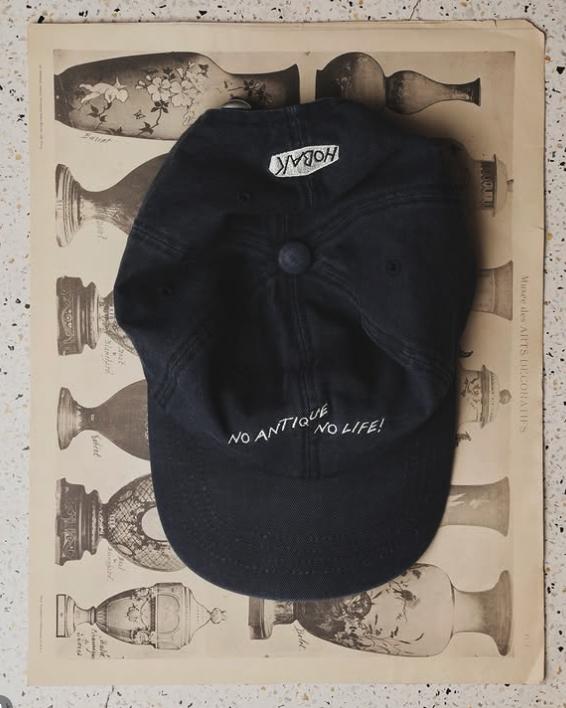 Washed black embroidered cap displayed on an antique print