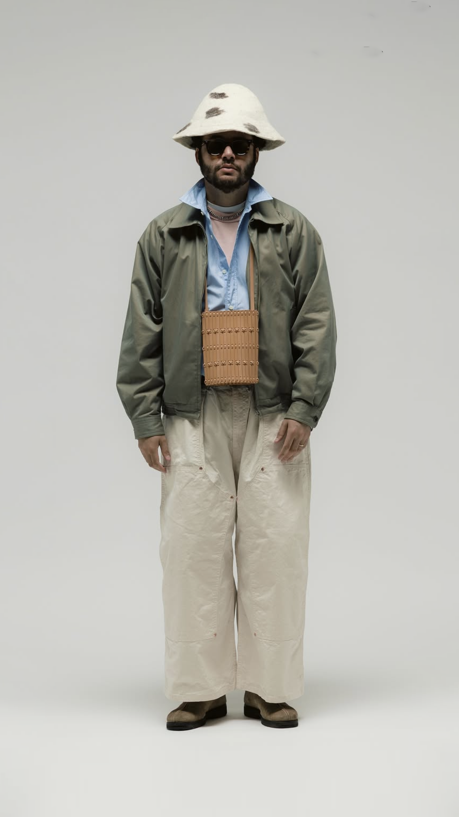 Front view of a wide cream trouser silhouette with olive jacket and felt hat