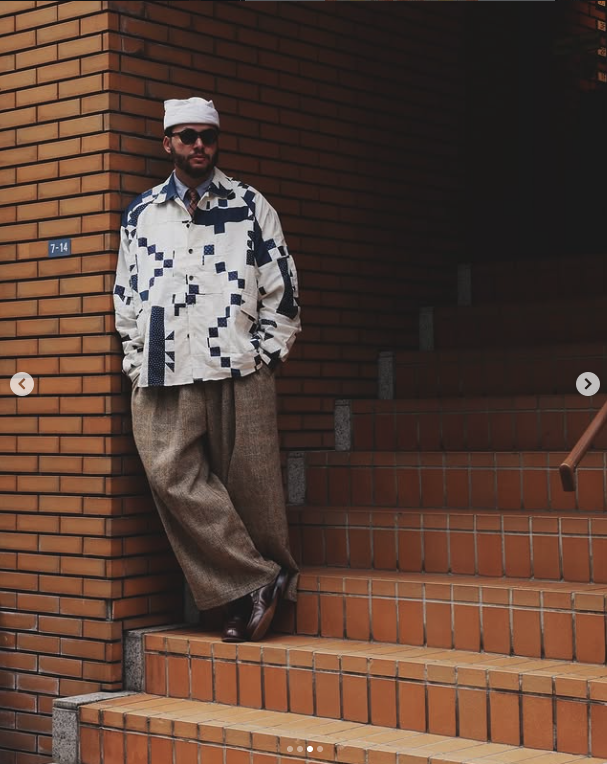 Graphic overshirt with wide textured trousers against brick architecture