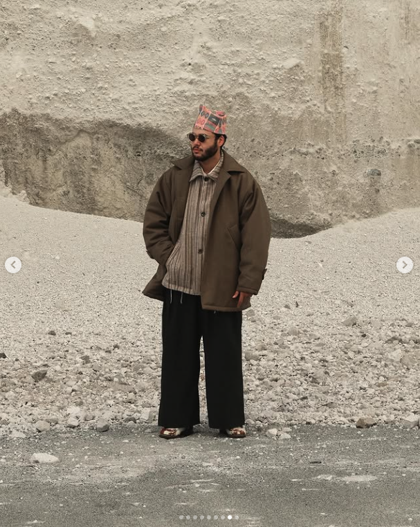 Brown layered outerwear with black wide trousers in a stone landscape