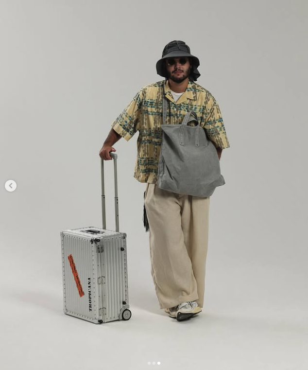 Printed shirt and relaxed cream trousers styled with a tote and travel case